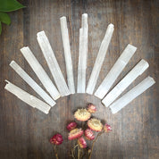 Selenite sticks fanned across table with flowers